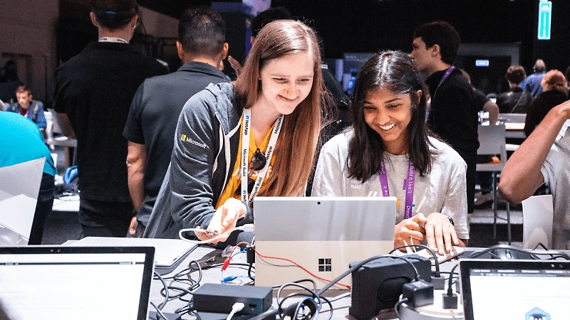 Two students smiling and working together on a Surface device.