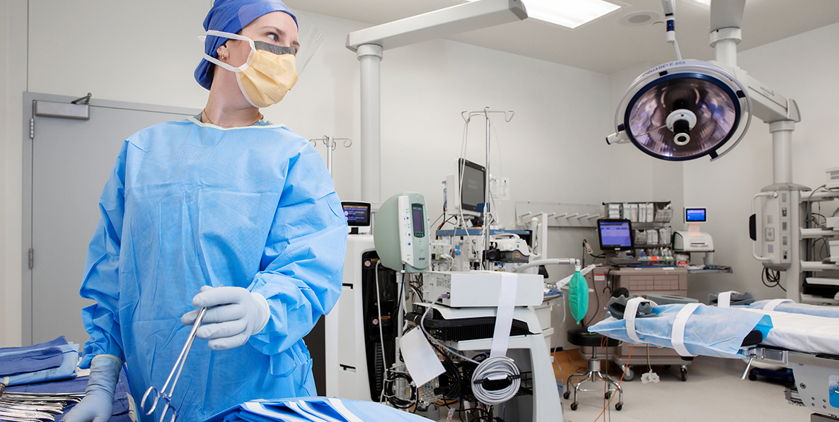 Female nurse wearing mask in operating room handling surgical instruments