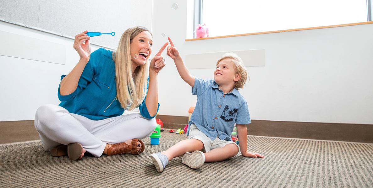  Female healthcare worker playing with bubbles with male pediatric patient