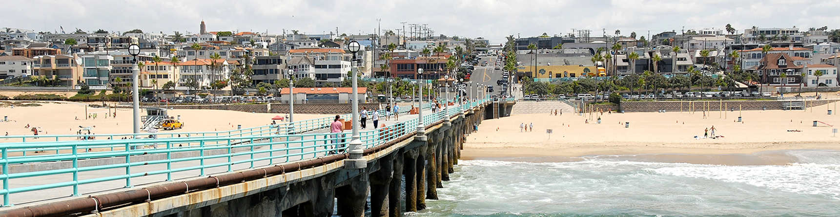 Looking down long pier toward beach with beachside community in background