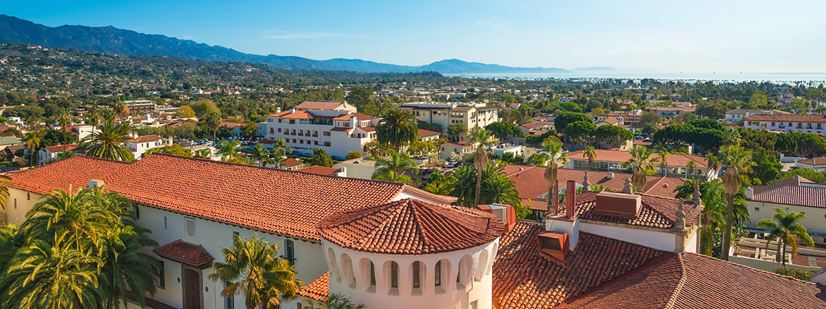 Aerial view of Santa Barbara buildings featuring historic Spanish architecture with mountains and ocean in background