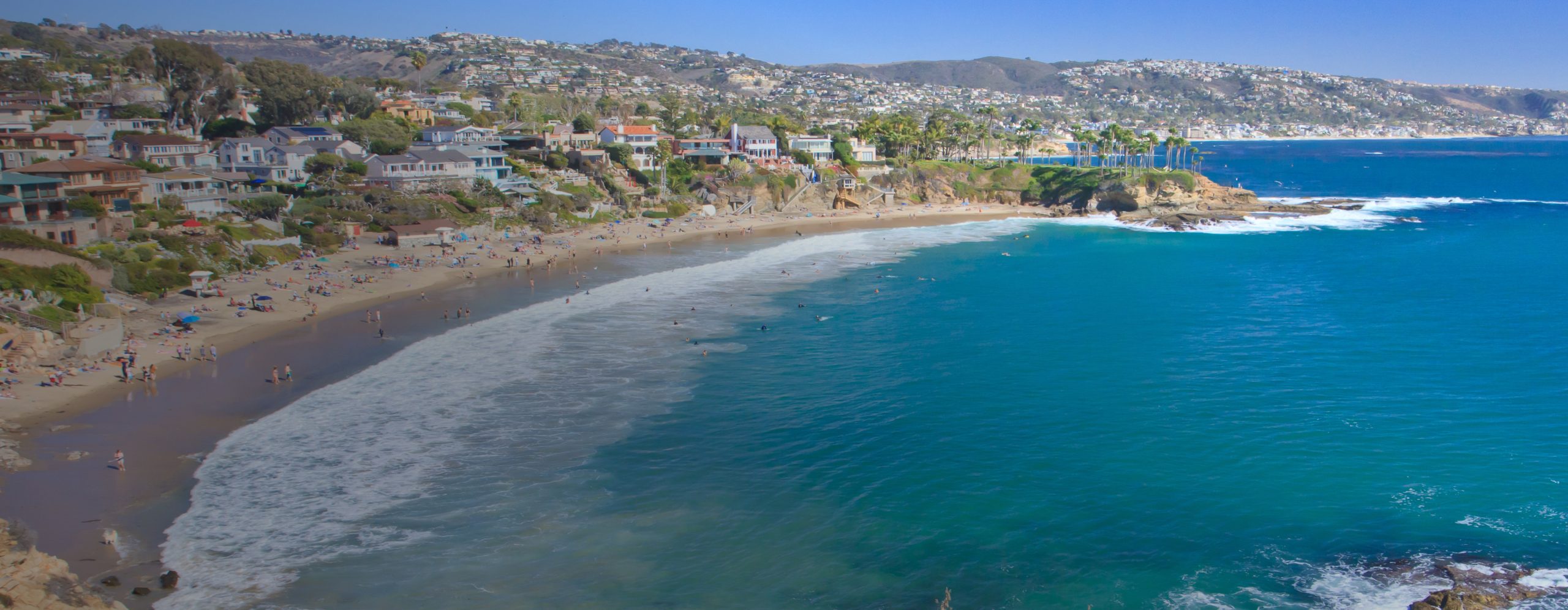 A stretch of the Southern California coastline with people on the beach in front of beachfront houses