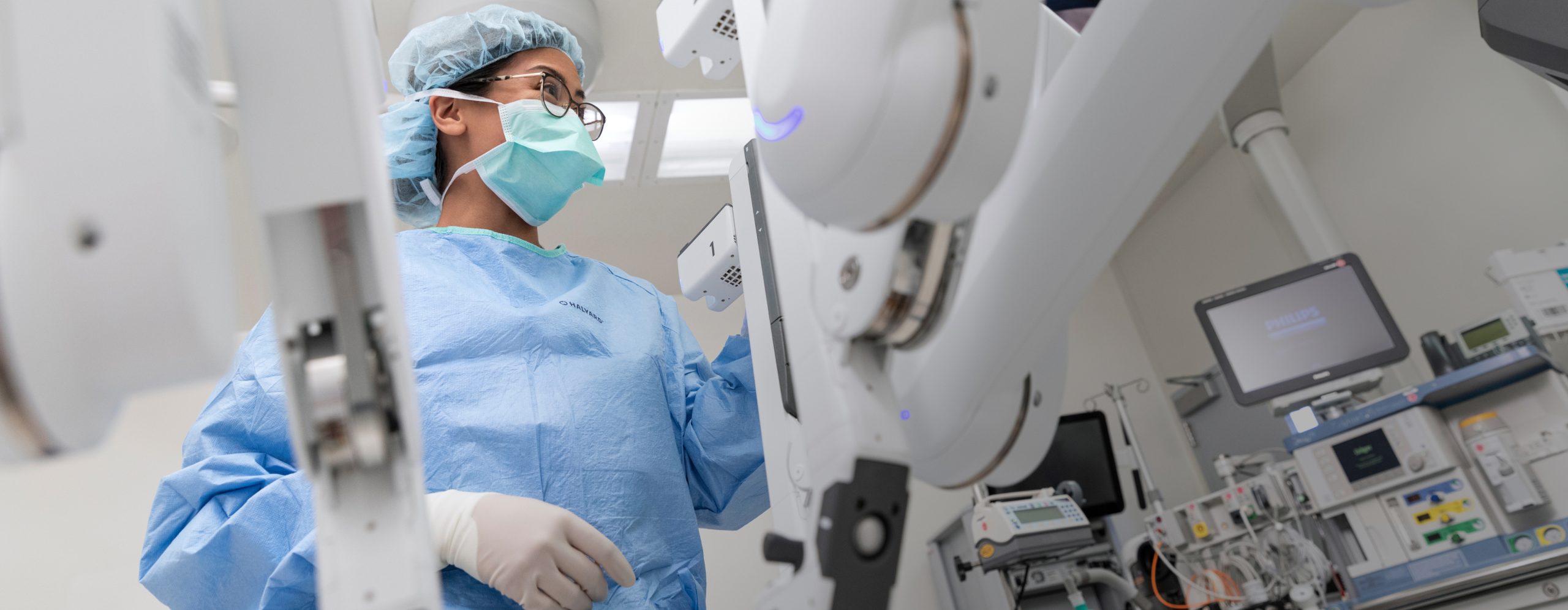 A female UCLA Health surgical professional working with a surgical robot in a state-of-the-art operating room