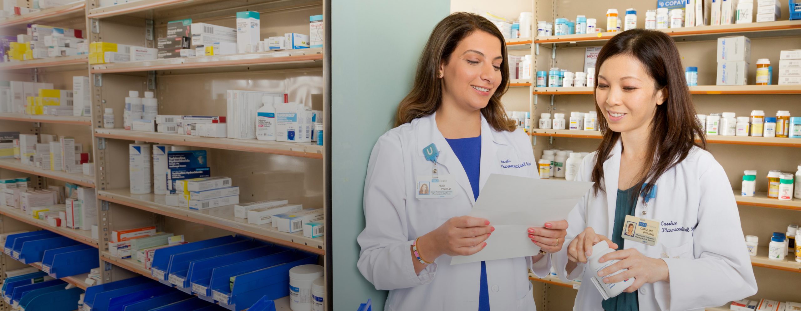 Two female UCLA Health pharmacists collaborating with a state-of-the-art UCLA Health pharmacy setting