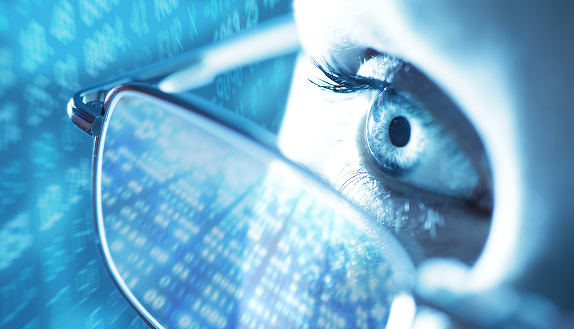 close up of a woman's eye with glasses on and digital images are reflected in her glasses and the background