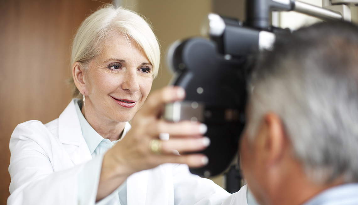 opthamologist uses a phoroptor to check a man's eyes