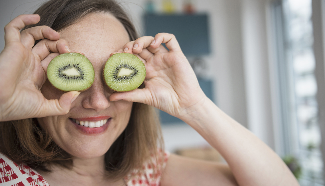 woman holding kiwis up to her eyes