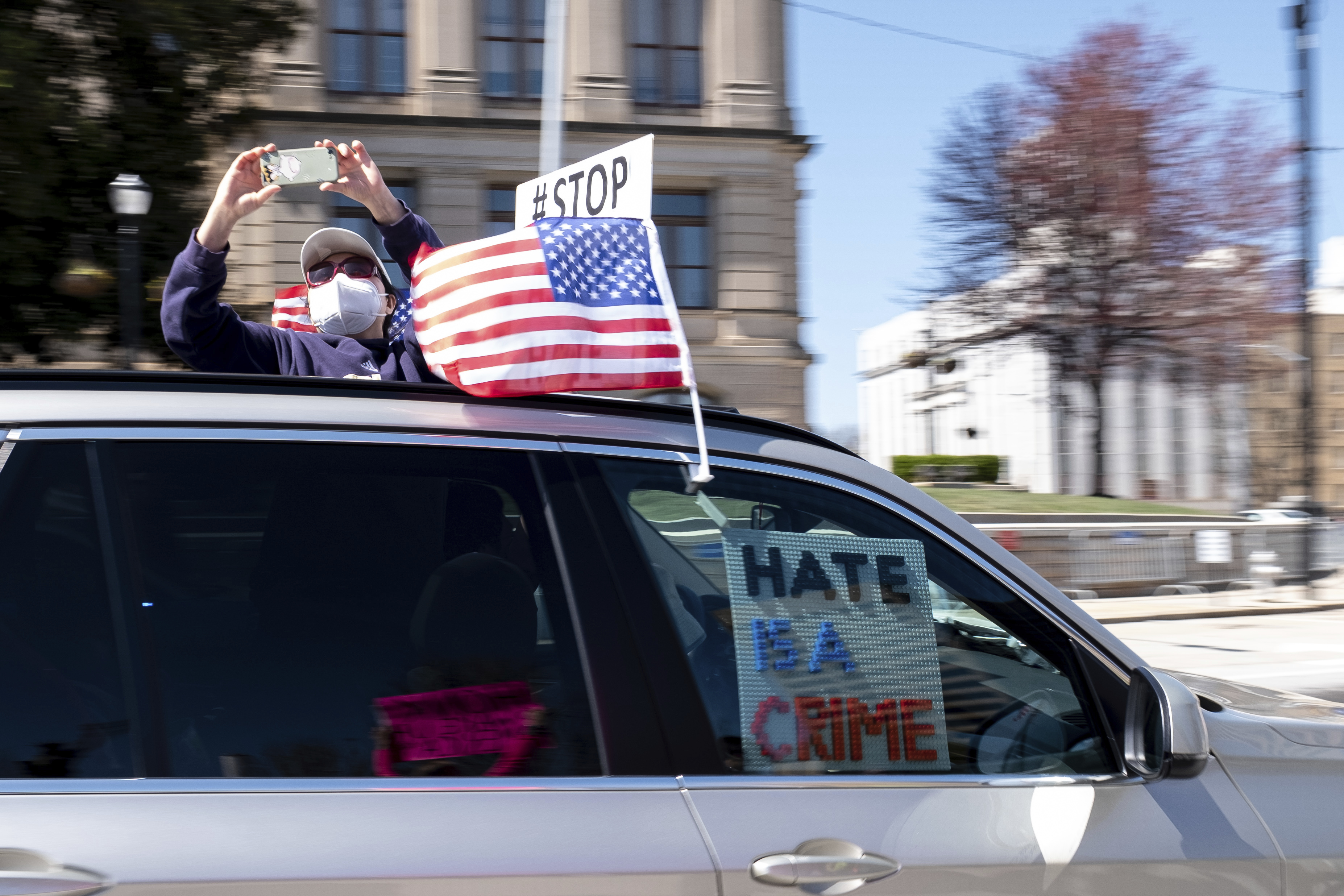 A person takes photos from their sunroof as they pass a "stop Asian hate" rally outside the Georgia State Capitol in Atlanta on Saturday afternoon, March 20, 2021.