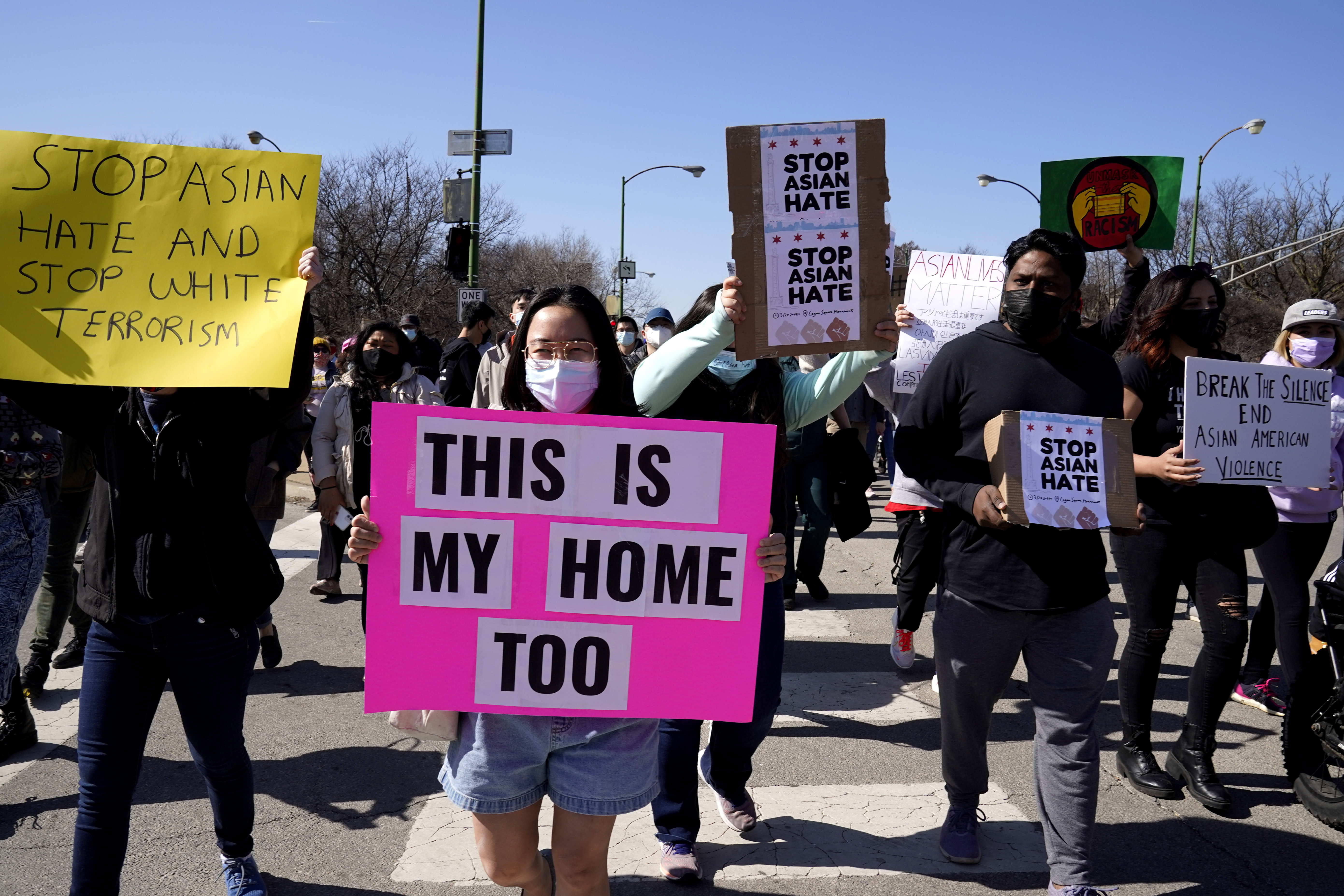 People hold signs as they march during a rally to support Stop Asian Hate at the Logan Square Monument in Chicago, Saturday, March 20, 2021.