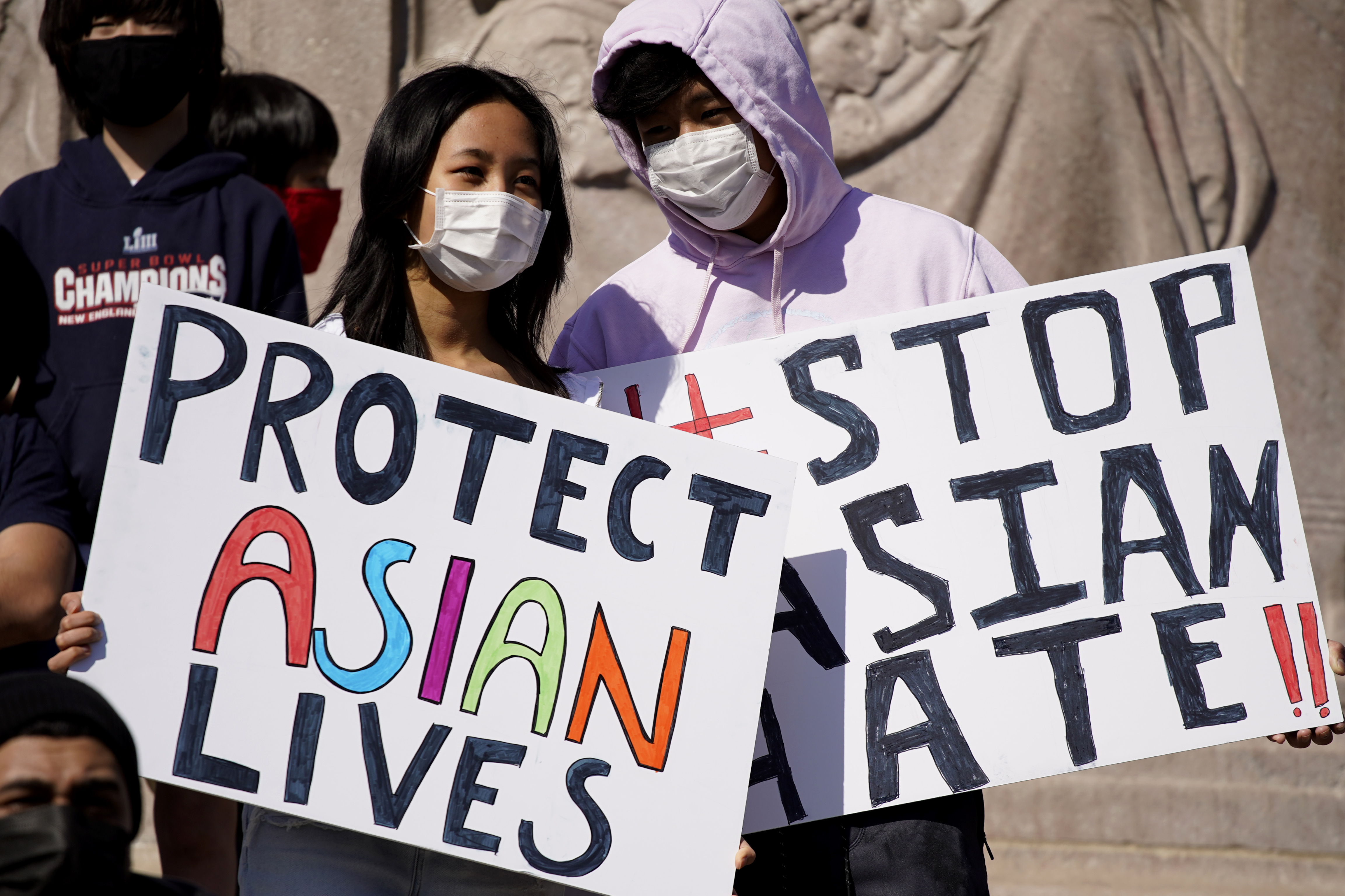 People hold signs as they attend a rally to support Stop Asian Hate at the Logan Square Monument in Chicago, Saturday, March 20, 2021.