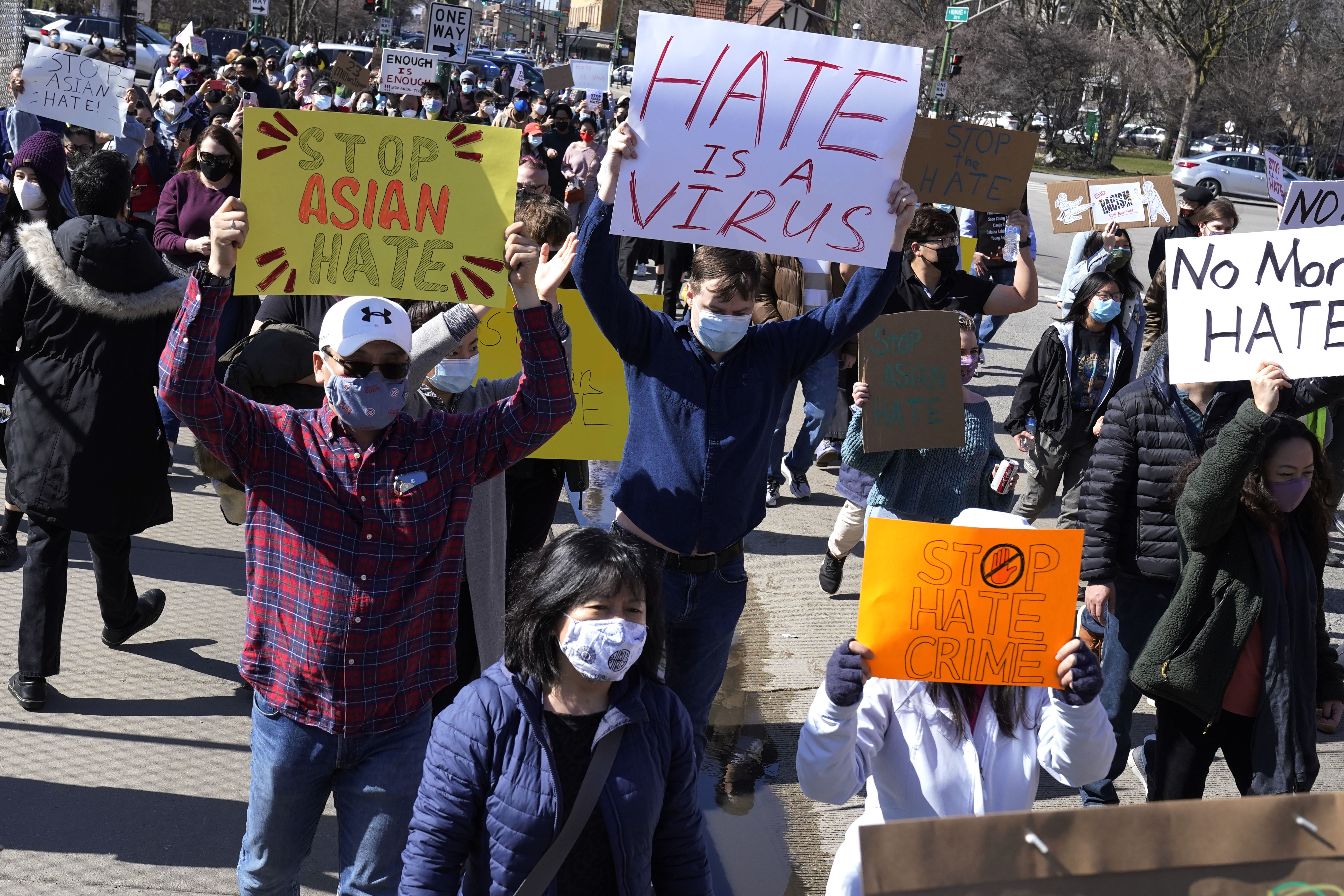 People hold signs as they march during a rally to support Stop Asian Hate at the Logan Square Monument in Chicago, Saturday, March 20, 2021.