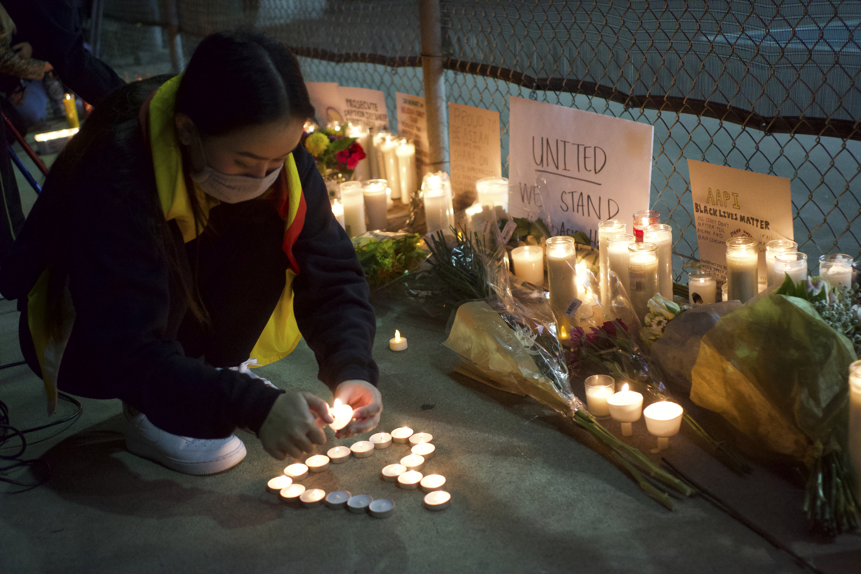 A woman lights candles at a rally "Stop Asian Hate" candlelight vigil at Almansor Park in Alhambra, Calif., Saturday night, March 20, 2021.