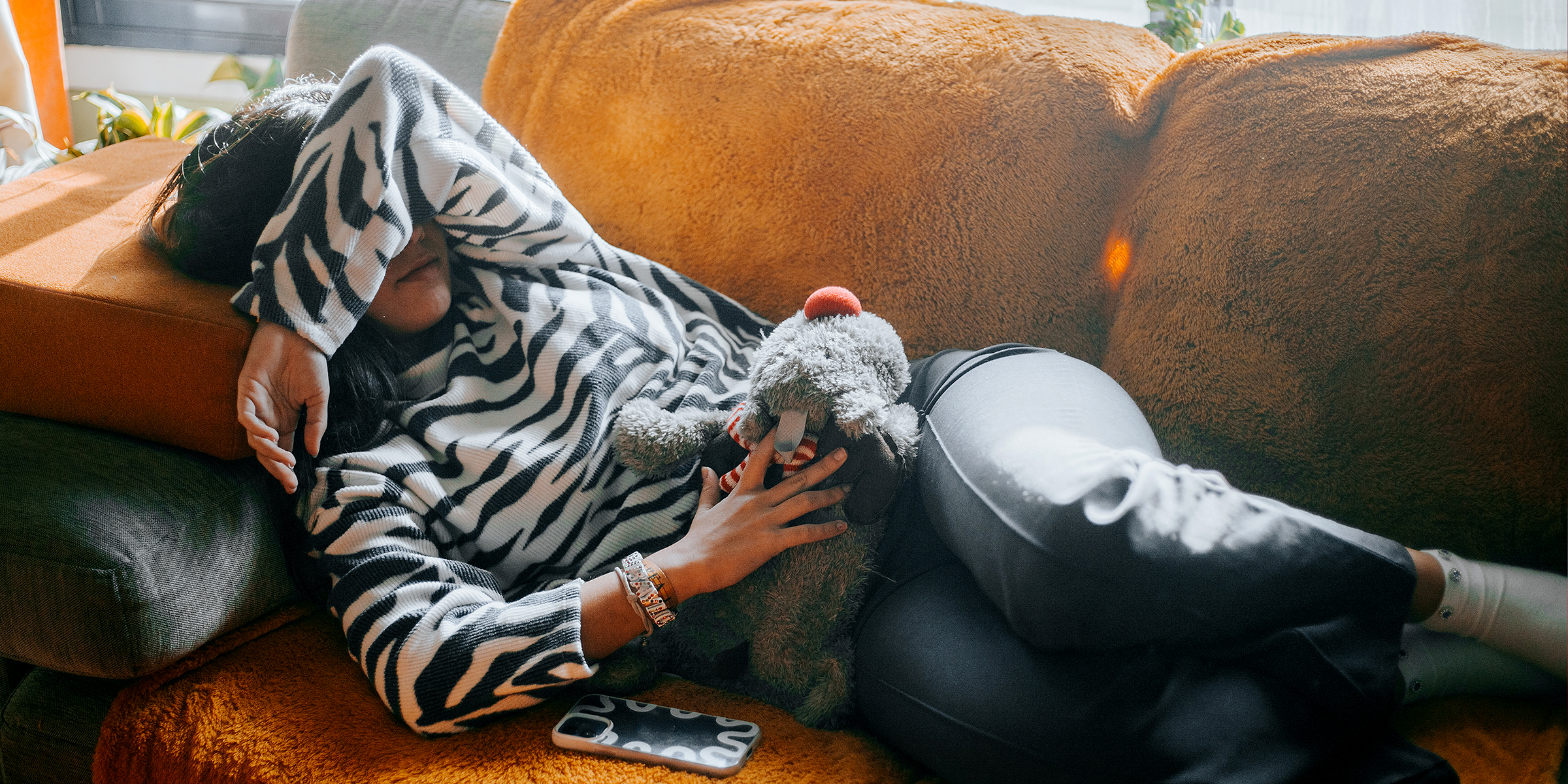 A sick woman suffering from pain lying on a sofa | Source: Getty Images