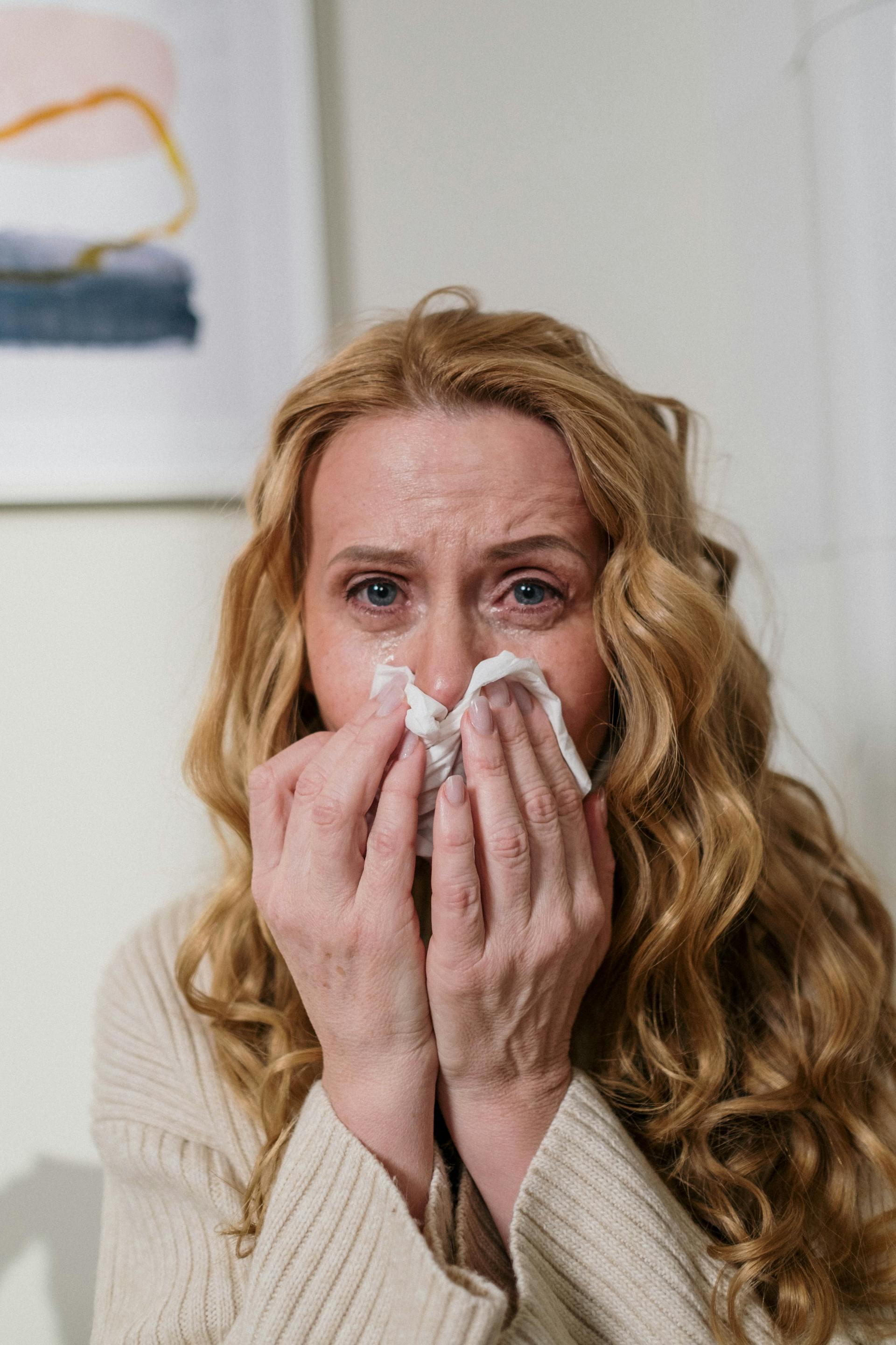 A woman wiping her nose with a handkerchief while crying | Source: Pexels