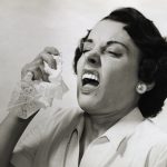 Picture shows a woman about to sneeze holding a handkerchief in her hand.