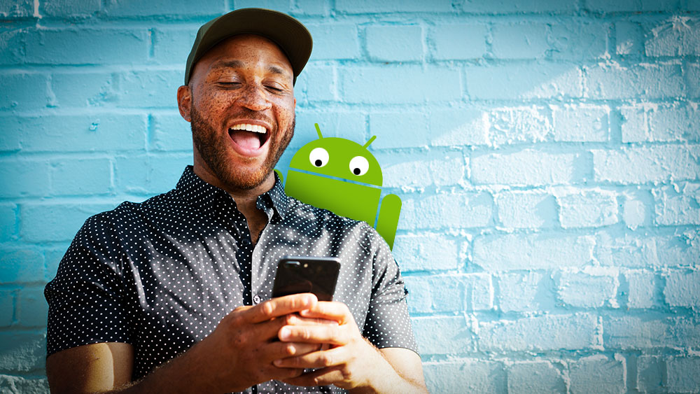 A man laughs at his smartphone while a cartoon characters peaks over his shoulder.