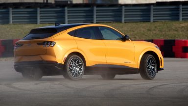 An orange Ford Mustang Mach-E GT burning rubber at an autocross