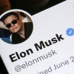 Photo illustration shows Elon Musk's Twitter profile on a phone screen, with a large Twitter logo in the background.