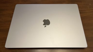 The top of a 16-inch MacBook Pro sitting on a table, with the Apple logo visible