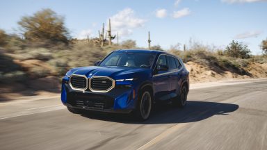 A blue BMW XM drives down a desert road