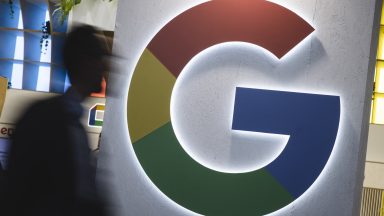 Large Google logo in the form of the letter "G" is illuminated at a conference booth.