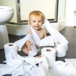 Toddler ripping up toilet paper in bathroom