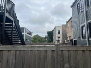 A fenced yard in a Chicago neighborhood with overcast skies