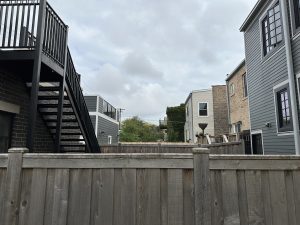 A fenced yard in a Chicago neighborhood with overcast skies