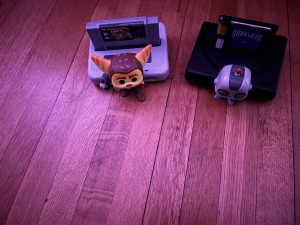 Two video game figurines beside consoles