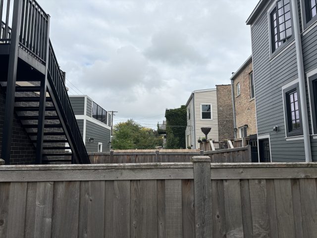 A fenced yard in a Chicago neighborhood with overcast skies