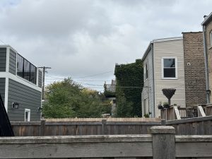 A fenced yard in a Chicago neighborhood with overcast skies