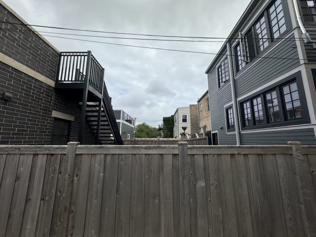 A fenced yard in a Chicago neighborhood with overcast skies