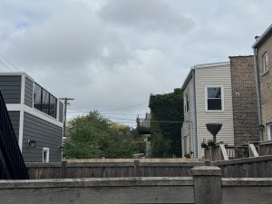 A fenced yard in a Chicago neighborhood with overcast skies