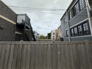 A fenced yard in a Chicago neighborhood with overcast skies