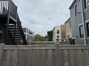 A fenced yard in a Chicago neighborhood with overcast skies