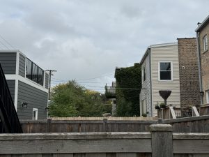 A fenced yard in a Chicago neighborhood with overcast skies