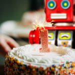 A toy tin robot blowing out a birthday candle.