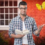 Man holding a book gesturing at a butterfly