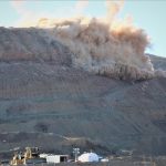 Image of a grey rocky face with part of it exploding.