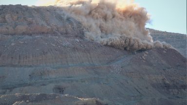 Image of a grey rocky face with part of it exploding.