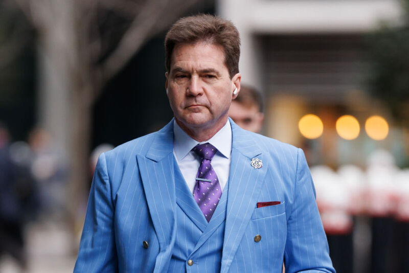 Craig Wright walking on the street, wearing a suit and tie.