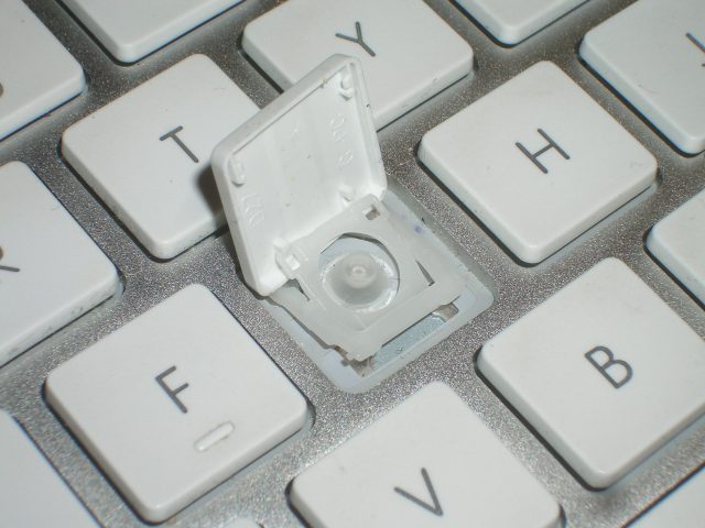 A close-up of the scissor switch under a keyboard's keycap.