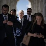 Apple CEO Tim Cook and other people walk through an archway while leaving the US Capitol building.