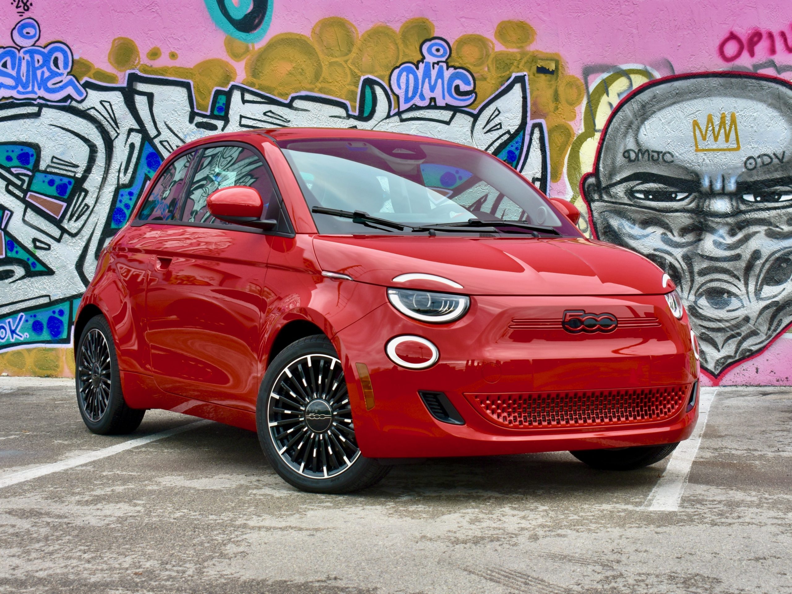 A red fiat 500e next to a mural