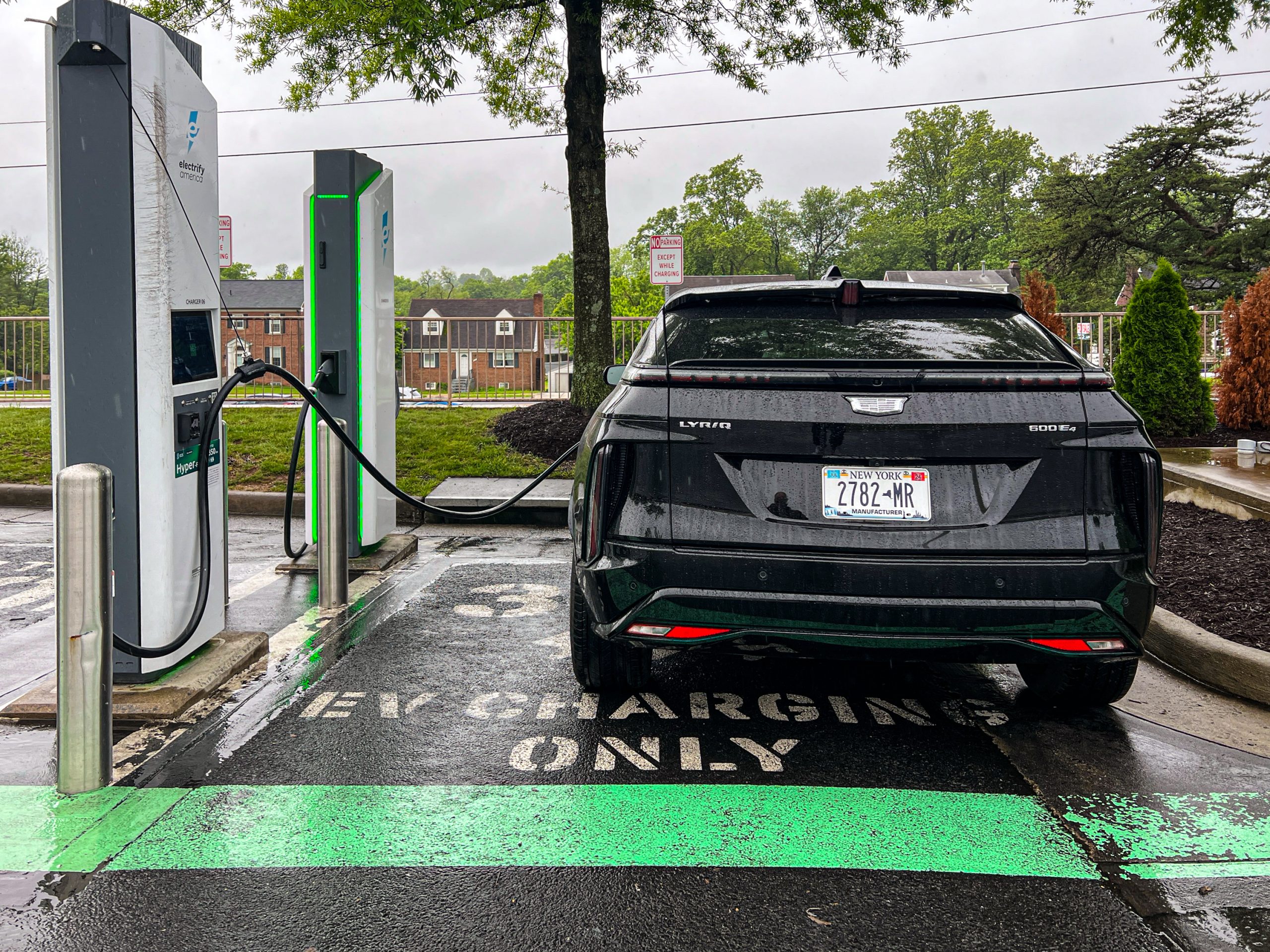 A Cadillac Lyriq plugged into a fast charger, seen from behind