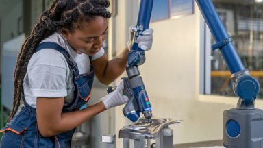 A woman performs maintenance on a robotic arm.