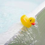 Rubber duck falling out of bath overflowing with water