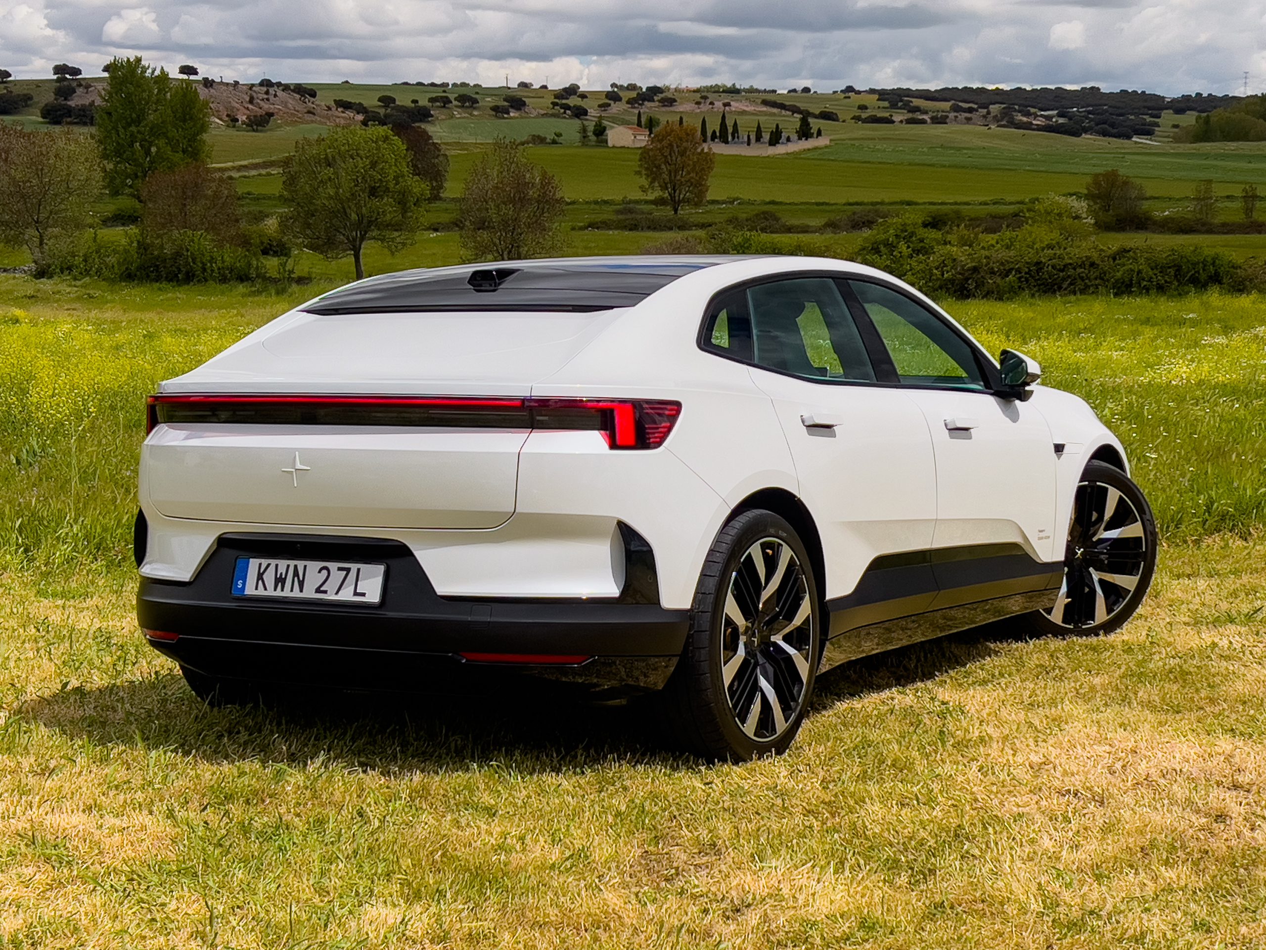 A white Polestar 4 in a field, seen from the rear 3/4