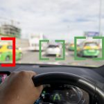 Image out the windshield of a car, with other vehicles highlighted by computer-generated brackets.