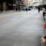 a person on a sidewalk in downtown Seattle, preparing to jaywalk across the street."